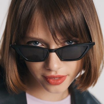Portrait of beautiful blue eyed girl with bob hair and red lips wearing sunglasses isolated on white background